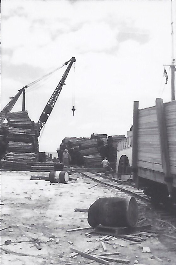 Lumber being loaded from narrow gauge rail car at Freeport Harbour